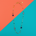 Collana lunga Bohèmien Blu e Lilla con perline multicolor su sfondo pop