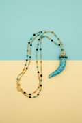 Collana corno ceramica turchese su sfondo pop turchese e giallo